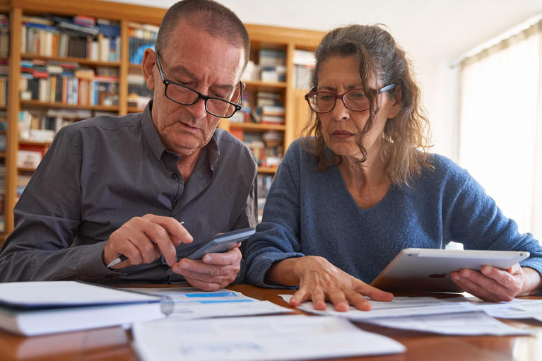 Two senior citizens sitting at a table with paperwork in front of them